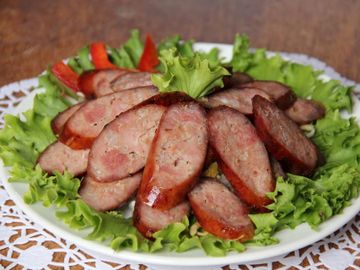 Sliced sausage arranged on lettuce with tomato garnish.