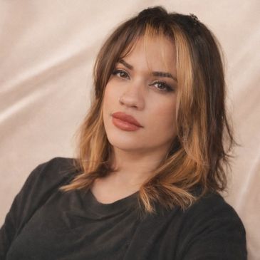 Young woman with highlighted hair and neutral expression.