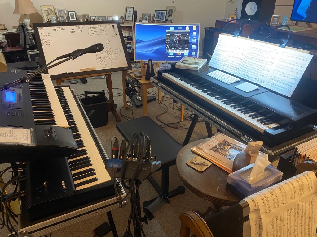 A music studio setup with keyboards, a microphone, and sheet music.