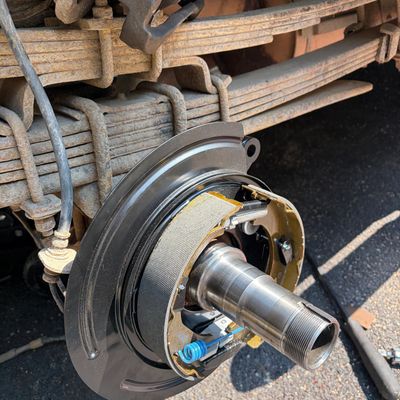 Close-up of a vehicle's rear drum brake assembly work in progress.