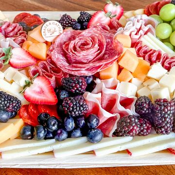 Colorful charcuterie board with fruits, cheeses, and meats artfully arranged.