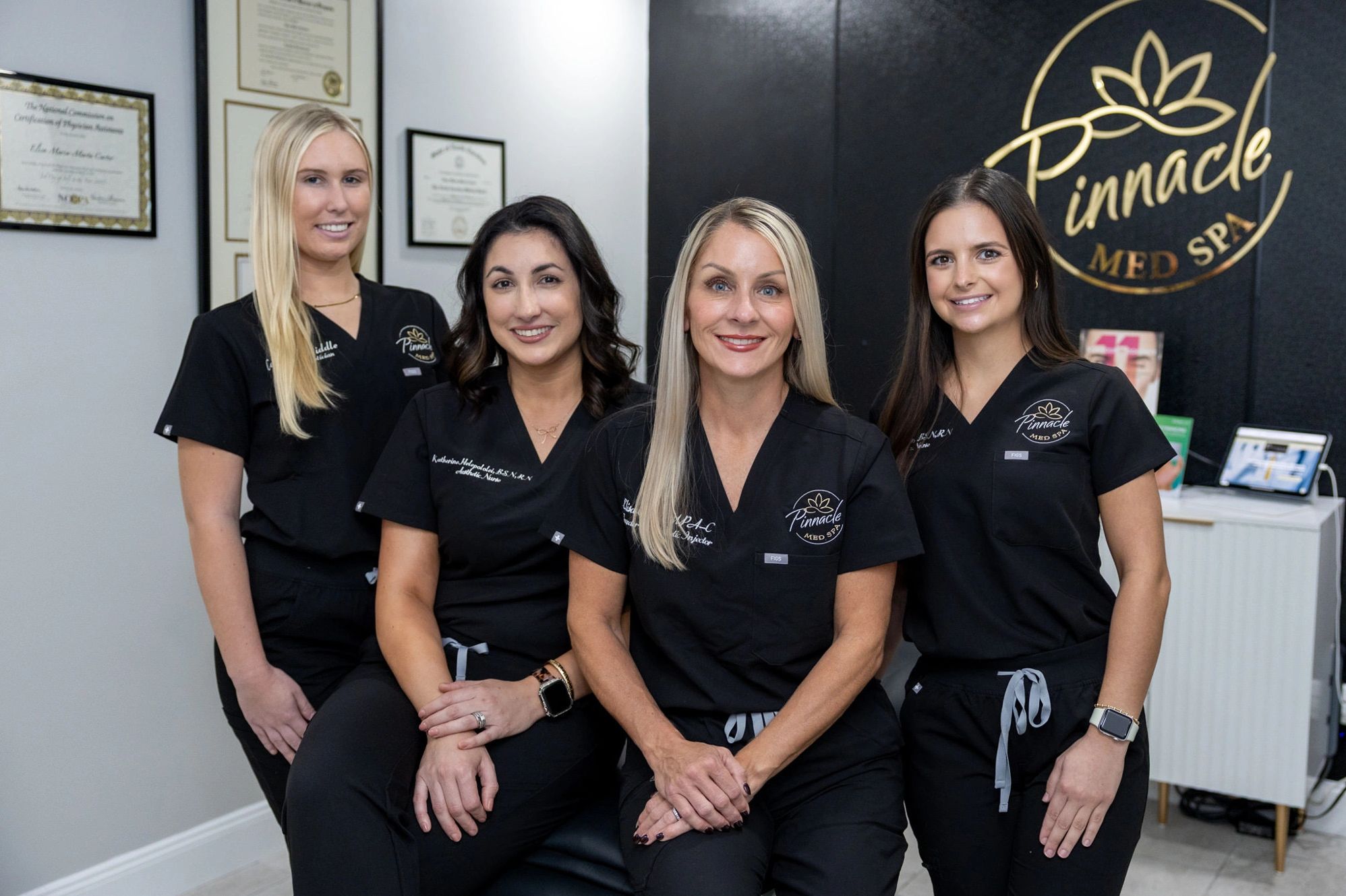 Four women in black medical scrubs posing in a med spa.
