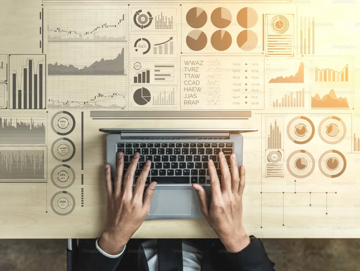 Person working on laptop surrounded by digital data charts and graphs.