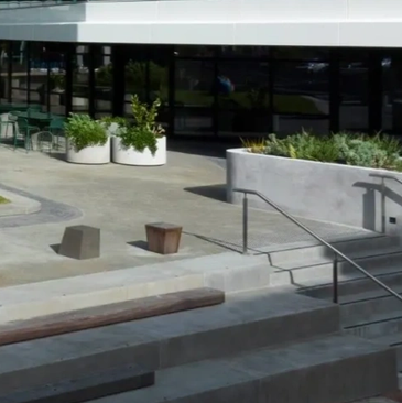 Modern outdoor seating area with concrete benches and planters near a building entrance.