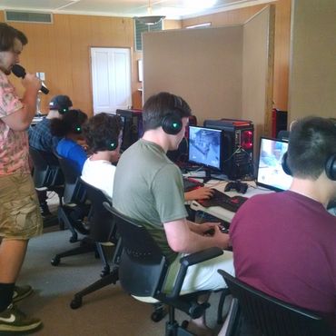 Group of people playing video games on computers in a room.