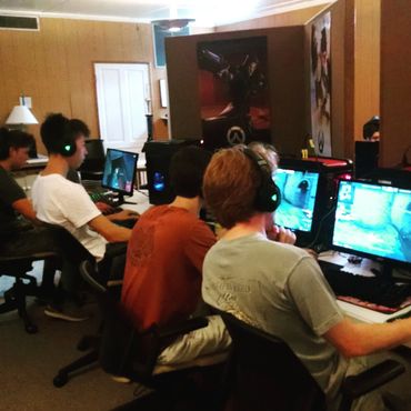 A group of young gamers intensely playing on desktop computers in a gaming room.