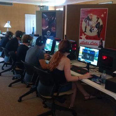 Group of people playing video games at computers in a gaming room.