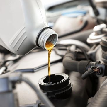 Pouring engine oil into a car engine.