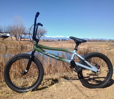 A BMX bike parked outdoors on dry grass under a clear blue sky.