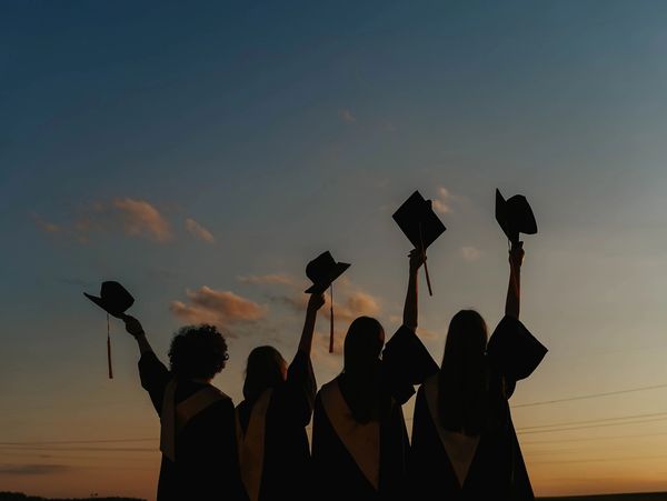 Graduates celebrating at sunset.
