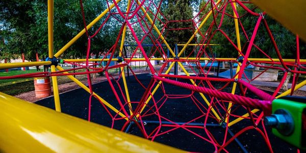 Colorful climbing ropes at a playground under trees.