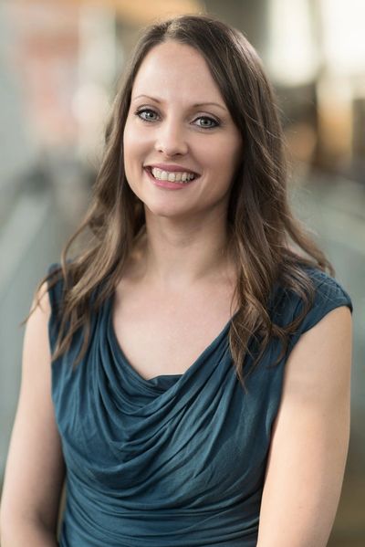 Smiling woman in a blue sleeveless top.