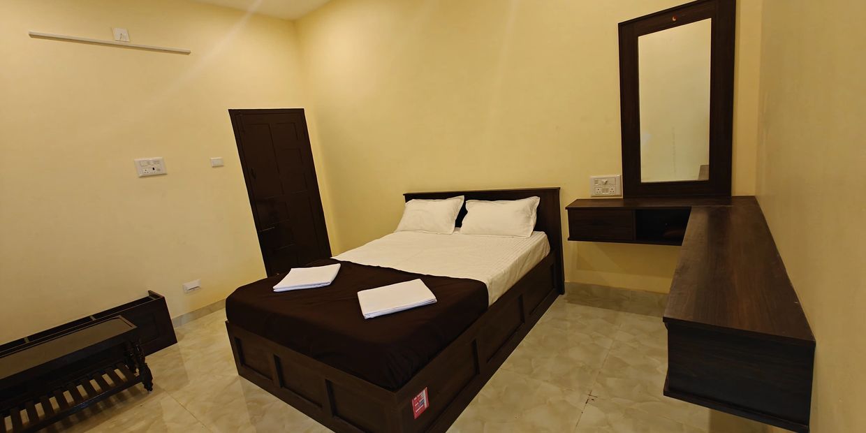 A simple bedroom with a double bed, towels, and wooden furniture.