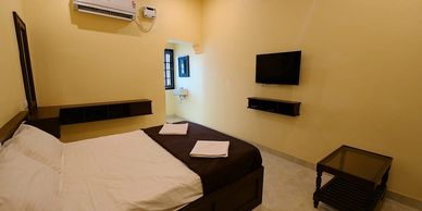 Minimalist bedroom with a bed, TV, and air conditioner.