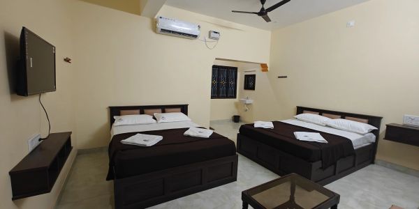 A clean, simple hotel room with two beds and modern amenities.
