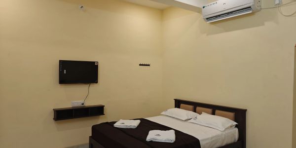 Minimalist bedroom with a bed, wall-mounted TV, and air conditioner.
