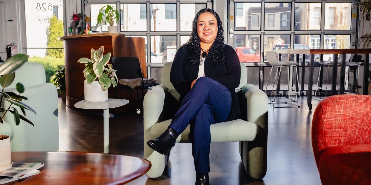 A woman seated confidently in a modern, stylish office lounge area.