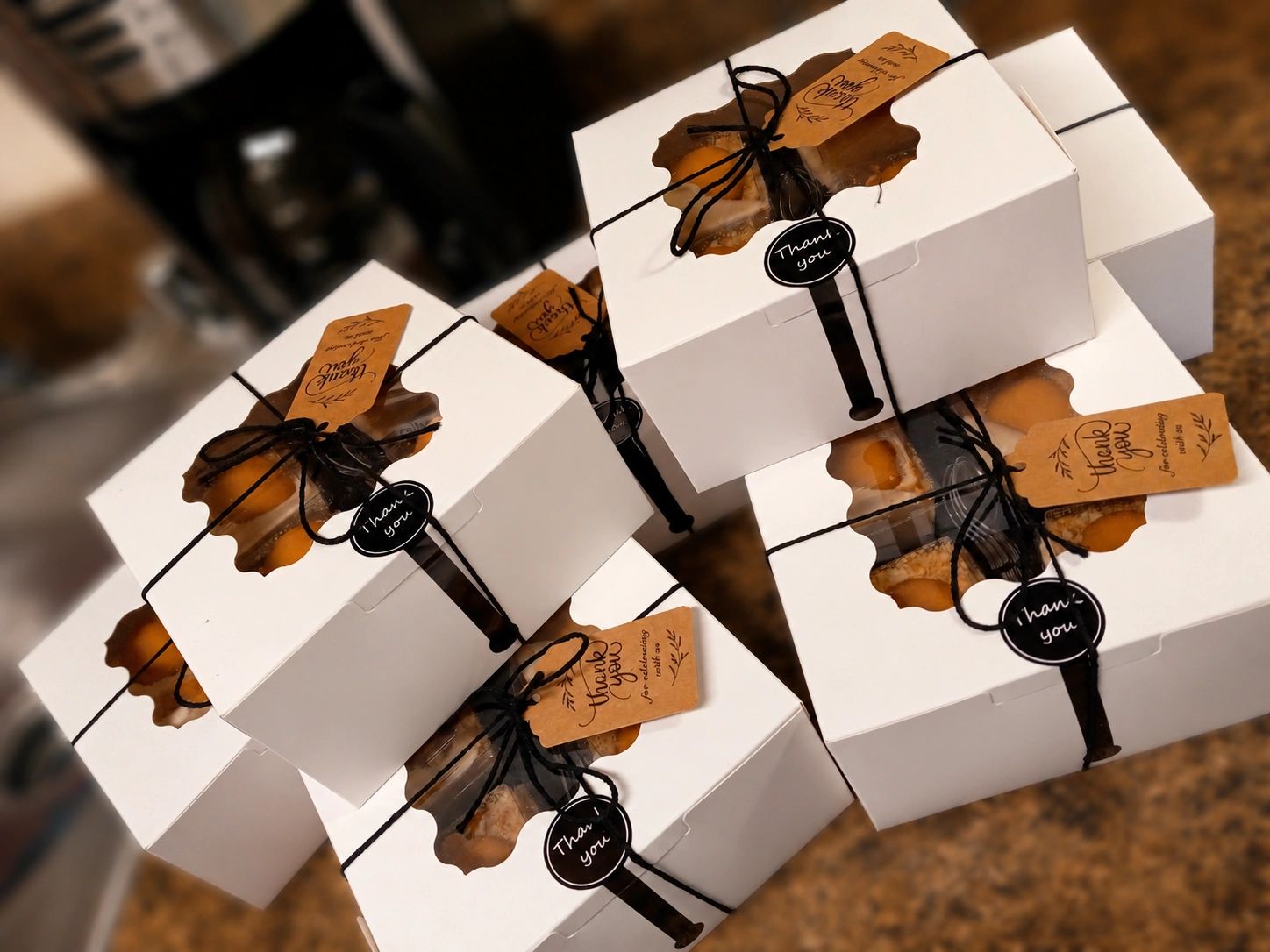 Stack of white gift boxes tied with black string and thank you tags.