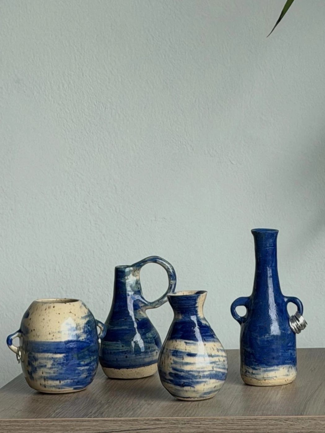 Four blue and beige ceramic vases on a wooden surface.