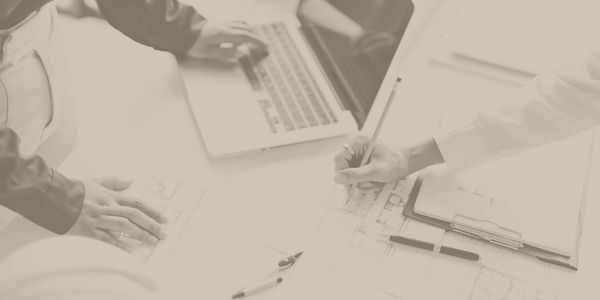 Professionals collaborating on architectural blueprints with a laptop and drafting tools.