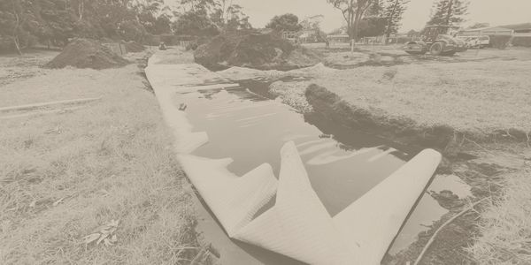 A partially lined trench filled with water at a construction site.