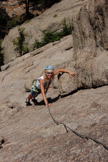 Young girl rock climbing with helmet and rope.