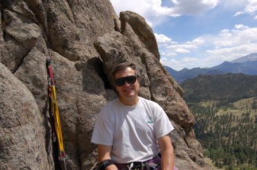 Man resting on rock during a mountain climb.