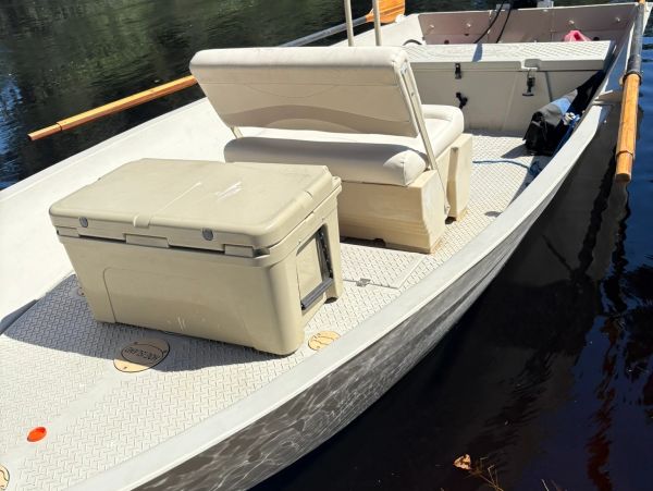 A small boat with a bench seat and cooler.