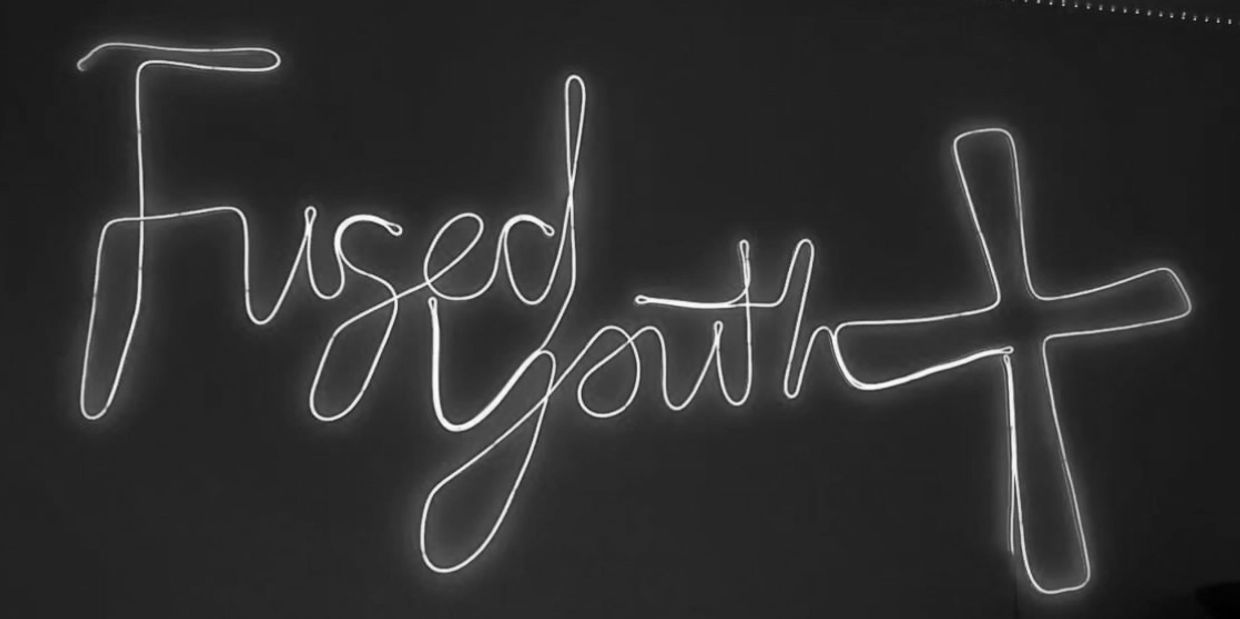 Purple neon sign reading 'Fused youth' with a cross symbol.