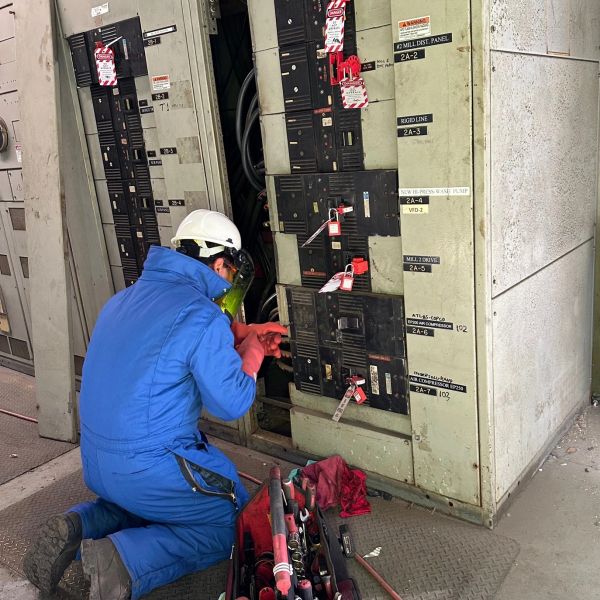 Worker kneeling to fix electrical panel.