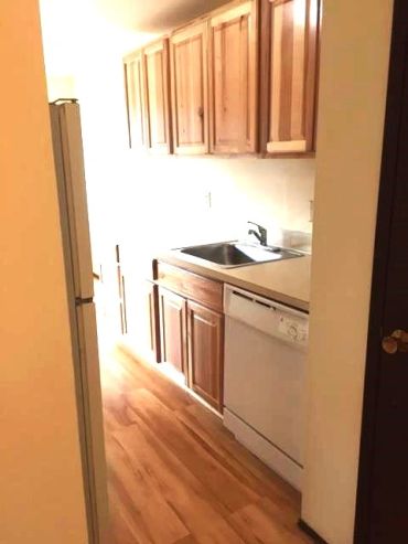 Small kitchen with wooden cabinets and white appliances.