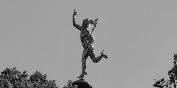 A photograph of a metallic statue of Hermes as seen in Stuttgart, Germany.