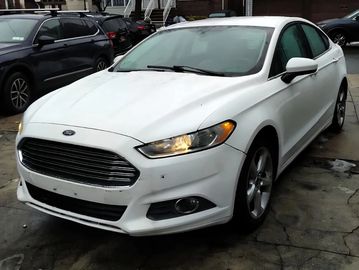 White Ford sedan parked on a wet concrete surface.