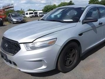 Silver sedan with a blacked-out grille parked outdoors on a sunny day.