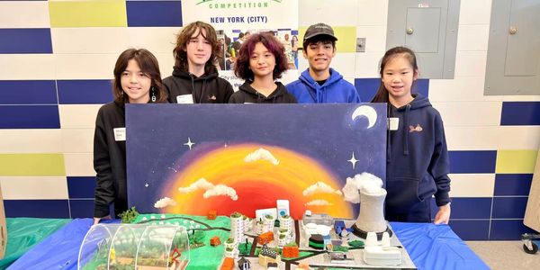 Five students proudly display their science project with a vibrant sunset backdrop.