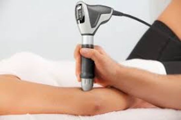 Therapist using a handheld device on a patient's arm for treatment.