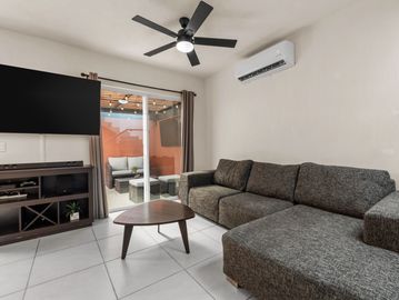 Sala moderna con sofá gris y televisión.