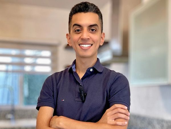 Young man smiling confidently with arms crossed in a modern kitchen.