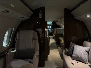 Luxurious cabin interior of a private jet with plush seating and ambient lighting.