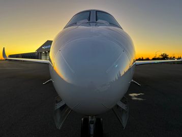 Front view of a private jet at sunset on the runway.