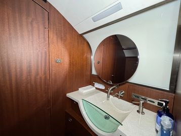 Modern bathroom with wooden cabinetry and a round mirror.