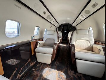 Luxurious private jet interior with spacious leather seats and large windows.