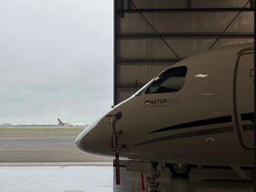 Close-up of a private jet nose inside a hangar with another plane in the background.