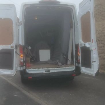 White van with open rear doors showing some equipment inside.