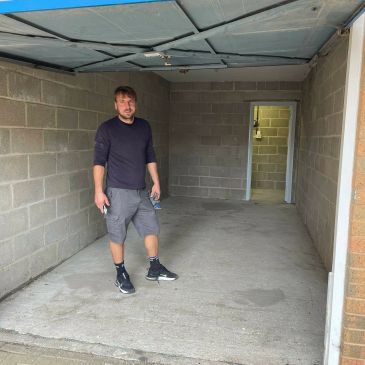 Man standing in an empty garage with concrete walls and floor.