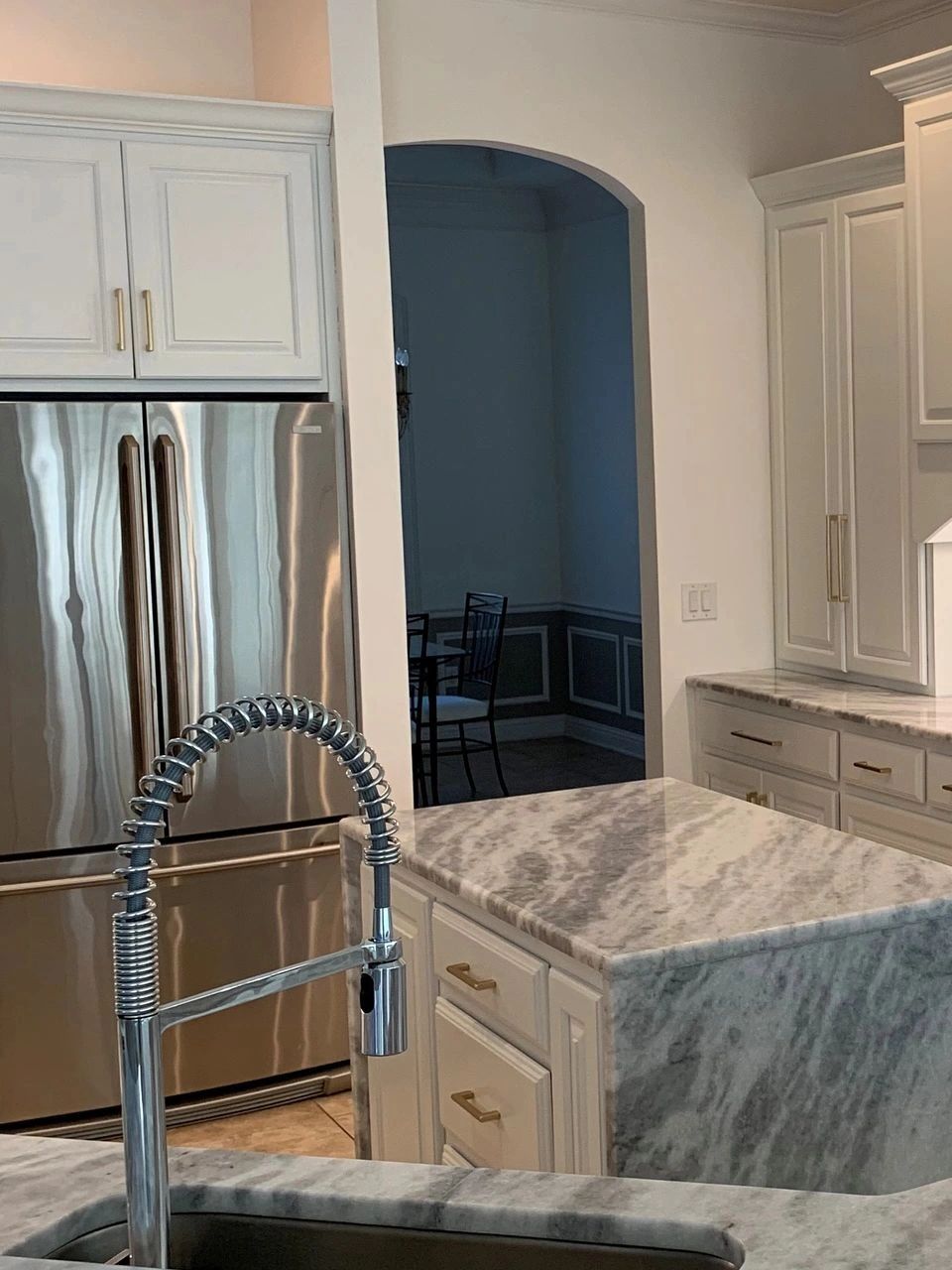Modern kitchen with marble countertops and stainless steel refrigerator.