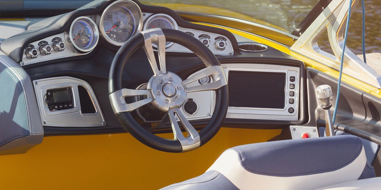 Modern boat dashboard with steering wheel and instruments.