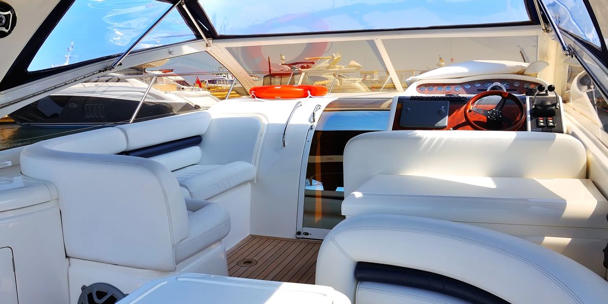 Luxurious white leather seating and helm on a modern yacht under clear blue skies.