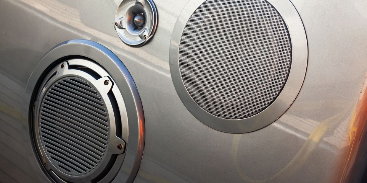 Close-up of three silver speaker grilles on a metallic surface.