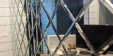 Patterned mirror with diamond shapes reflecting a room.